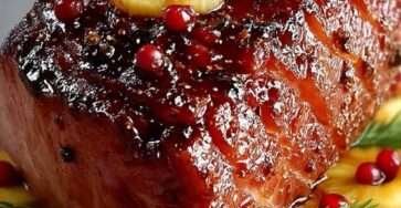 Rôti de jambon glacé au miel avec tranches d’ananas et cranberries caramélisées sur un plat de fête