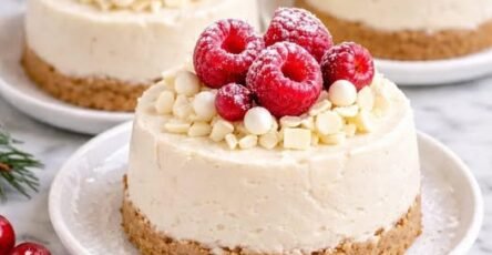 Petits gâteaux individuels crémeux à la vanille et au mascarpone sur base de biscuits, décorés de framboises et copeaux de chocolat blanc