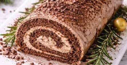 Bûche de Noël au chocolat et mascarpone roulée, décorée de cacao et copeaux de chocolat sur un plat festif
