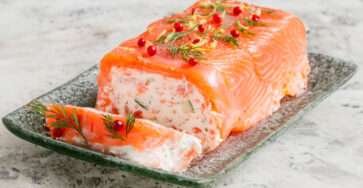 Tranches de bûche salée au saumon fumé et frais, au fromage de chèvre et concombre, décorées d’aneth et de citron vert sur un plat de fête