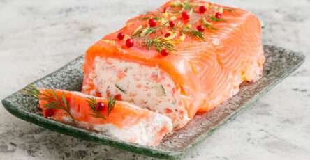 Tranches de bûche salée au saumon fumé et frais, au fromage de chèvre et concombre, décorées d’aneth et de citron vert sur un plat de fête