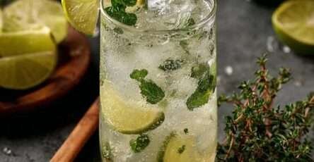 Verre de mojito sans alcool au citron vert, menthe fraîche et glaçons pétillants sur une table d’été