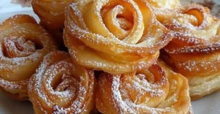 Roses de pommes feuilletées dorées, roulées en forme de fleurs dans des moules à muffins.
