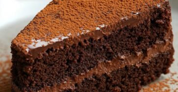 Gâteau au yaourt chocolaté ultra gourmand nappé de ganache, saupoudré de cacao, présenté sur une assiette de dessert.