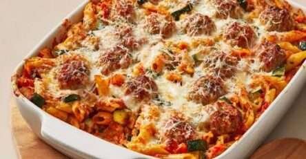 Gratin de pâtes aux boulettes de bœuf, courgette et fromage gratiné dans un plat familial au four