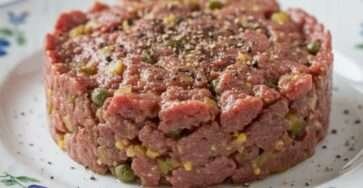 Assiette de tartare de bœuf aux câpres dressé au cercle avec échalote, cornichons et jaune d’œuf.