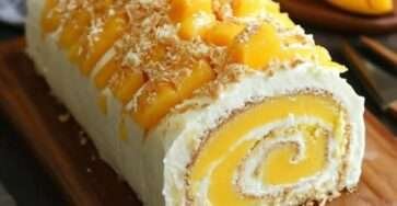 Gâteau roulé à la mangue garni de crème mascarpone à la mangue et saupoudré de sucre glace.