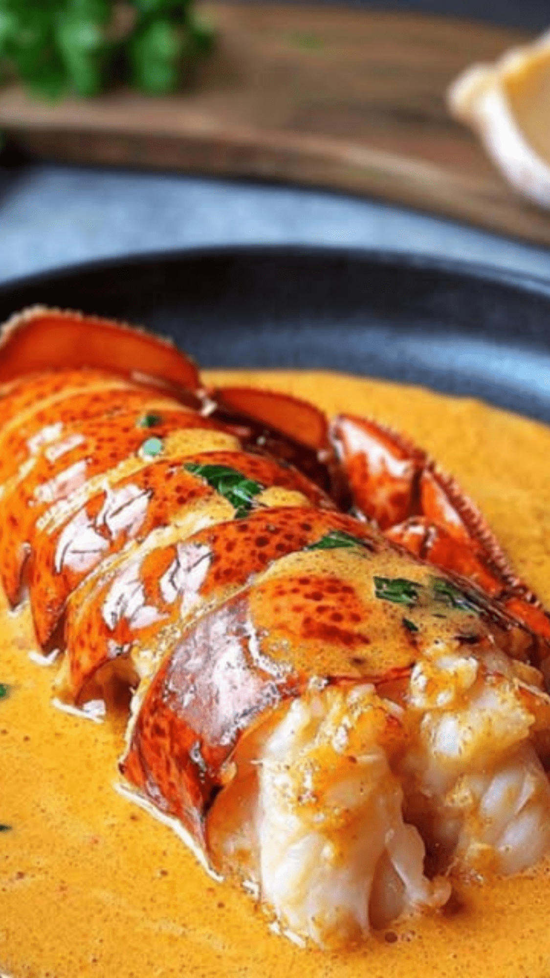 Queues de homard servies dans leur carapace, nappées de sauce homardine au Cognac, avec accompagnement raffiné sur assiette de fête